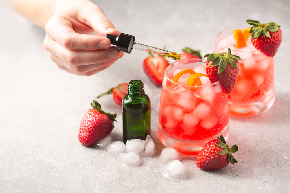 Person Putting Drops In Drink With Strawberries