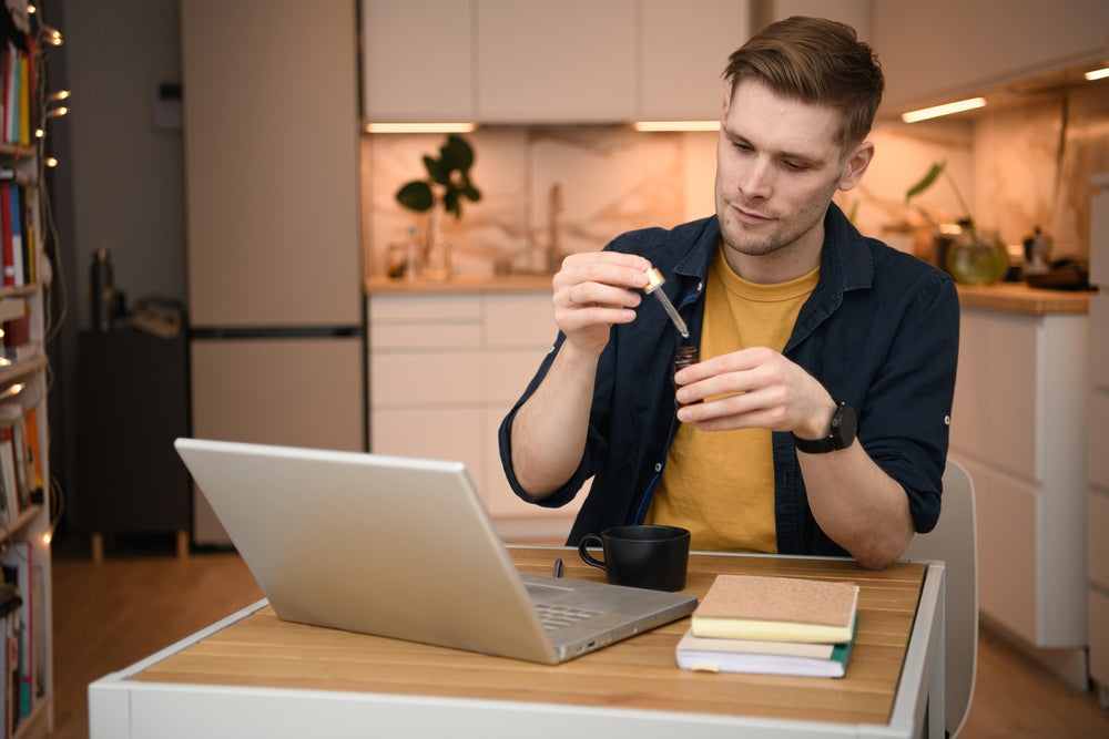 Man With Laptop Using Glass Dropper