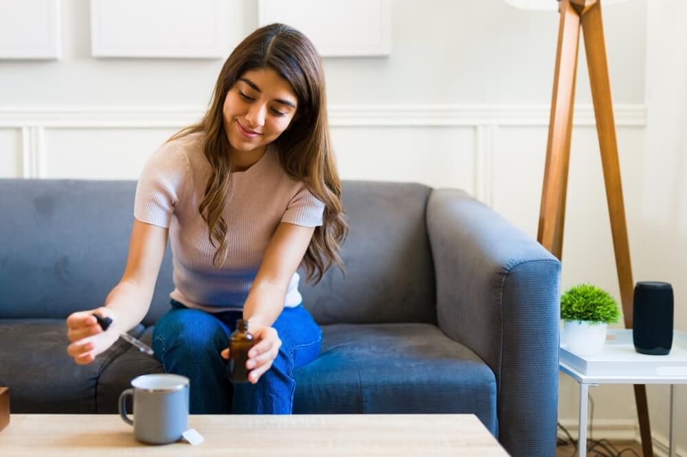 Lady Sitting On Couch Using Glass Dropper For Mug