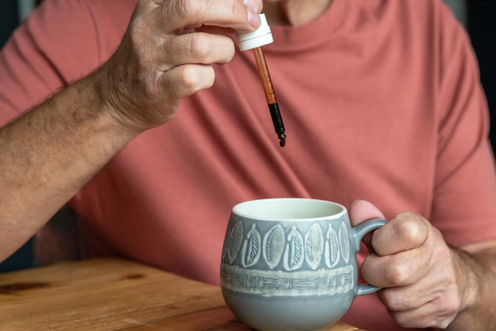 Man Using Glass Dropper Into Mug